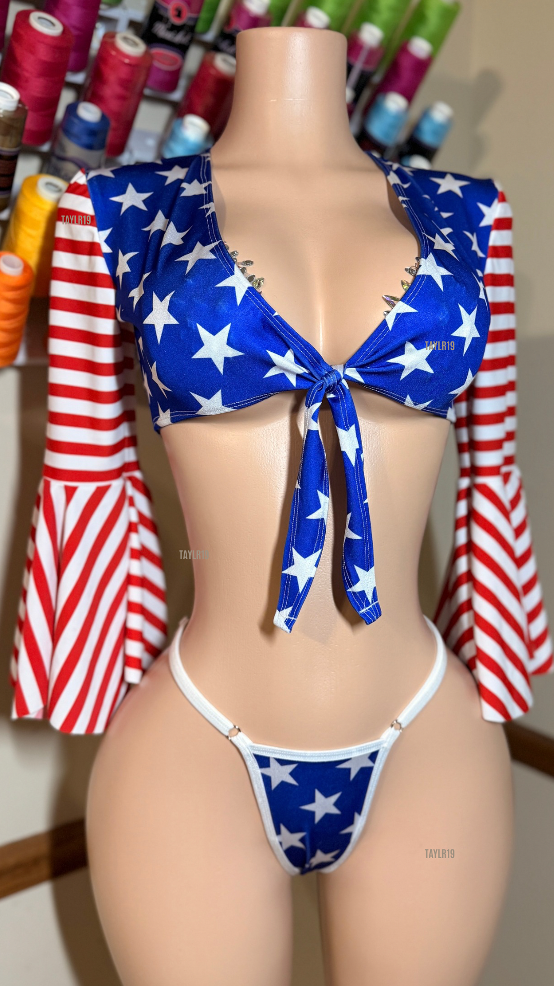 Women’s patriotic slingshot set featuring a tie-front crop top with dramatic bell sleeves and an adjustable slingshot bottom. Handmade exotic dancewear for entertainers, festivals, and themed events by Taylr19.